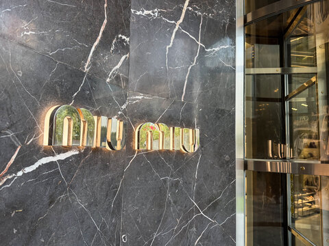 Shanghai, China - November 24, 2025: Miu Miu Logo on Dark Marble Facade Close Up