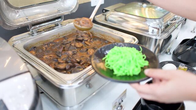 Catering Server Scooping Shiitake Mushroom Stew onto Jade Noodles at Buffet