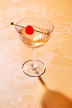 Cocktail with Cherry Garnish on Warm Marble Bartop