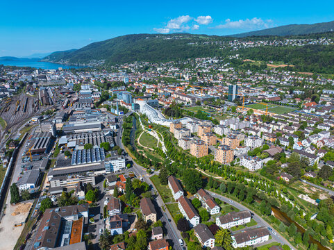 Aerial view of the modern Swatch headquarters and industrial zones surrounded by residential blocks and green parks in Biel Bienne, Canton of Bern, Switzerland.