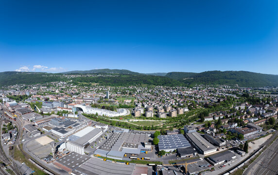 Aerial view of the Swatch and Omega headquarters with its unique curved architecture, surrounding industrial complexes, and residential districts Biel Bienne, Canton of Bern, Switzerland.