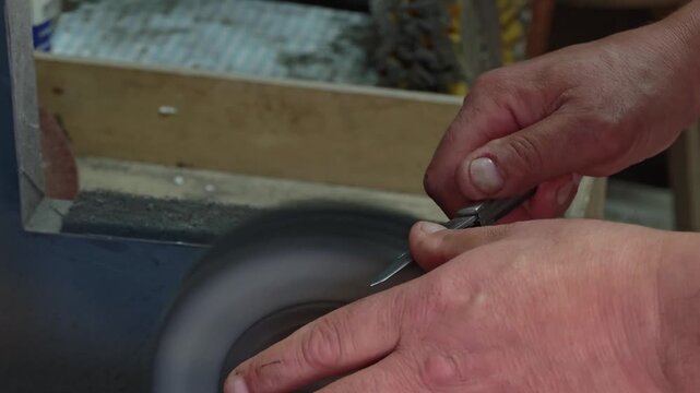Professional Knife Sharpening in 4K Slow Motion &ndash; Close-Up of Craftsman Honing Folding Knife Blade on Rotating Sharpening Stone, Precision Blade Maintenance Workshop