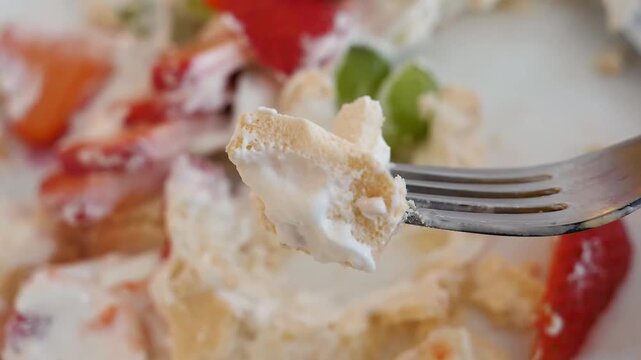 A close-up shot of a delicious, creamy dessert featuring fresh sliced strawberries, green kiwi, and crushed cookies or graham crackers folded into a thick, fluffy whipped cream or cheesecake mixture