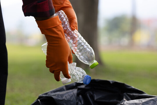 Volunteer collecting plastic bottles during environmental cleanup, promoting recycling, sustainability, and global responsibility for protecting nature and reducing pollution.
