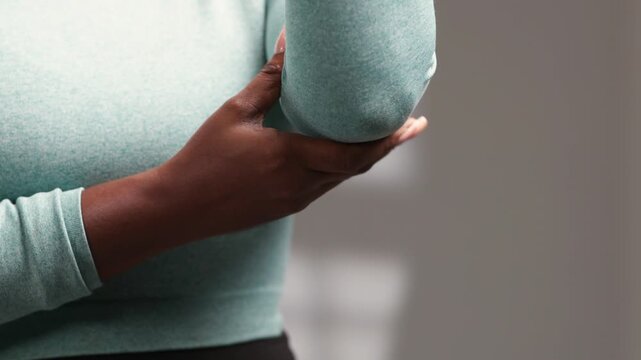 African woman holding her painful elbow joint, indicating discomfort and injury