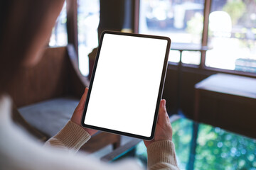 Mockup image of a woman holding digital tablet with blank white desktop screen in cafe