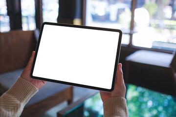 Mockup image of a woman holding digital tablet with blank white desktop screen in cafe © Farknot Architect