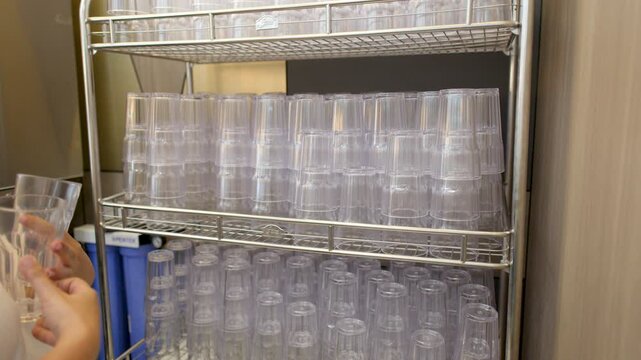 Person Reaching for Plastic Cups on Metal Shelf in Bangkok Buffet