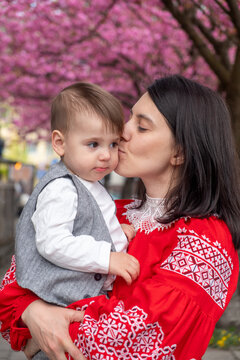 Mother kissing toddler under cherry blossoms in spring Portrait