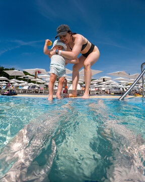 Mother and toddler playing in shallow resort swimming pool.