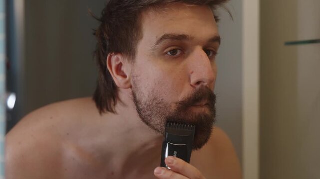 Shirtless man shaving beard in bathroom (4k60p)