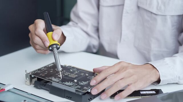 Computer engineer using a soldering iron fix graphic card