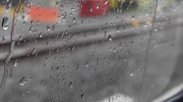 Raindrops on a moving train window with a blurred view of railway tracks and green landscapes passing by, creating a moody and melancholic travel atmosphere.