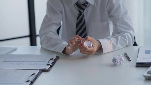Asian businessman crumpled the paper and throwing on table
