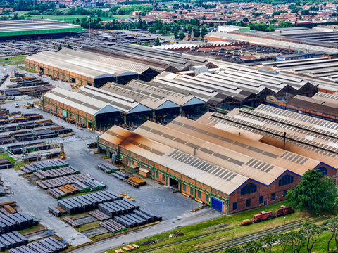 Aerial view of the vast industrial complex and steel pipe manufacturing facility with large warehouses and storage yards in Dalmine, Lombardy, Italy.