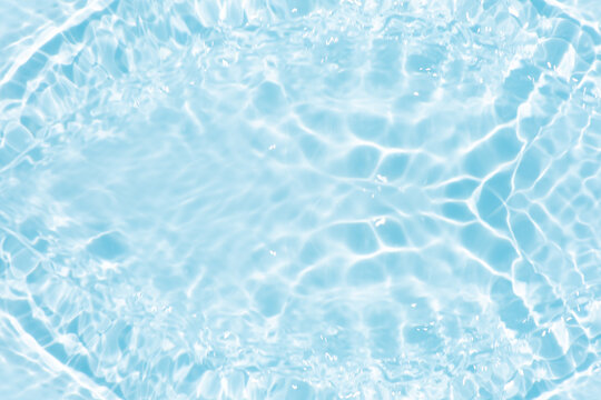 Blue water with ripples on the surface. Defocus blurred transparent blue colored clear calm water surface texture with splashes and bubbles. Water waves with shining pattern texture background.
