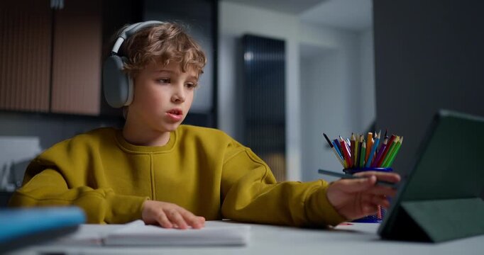 Young Man Diligently Engages In Reading And Writing Exercises Utilizing Electronic Tools In Evening Lighting