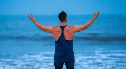 Male body stands in shallow water. Body opens arms to horizon. Body feels harmony and calmness. Body enjoys meditation and wellness. © Volodymyr