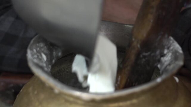 Extreme close up shot of making lassi from curd in vessel. Indian food preparation and dairy mixing process.