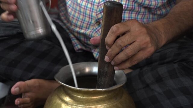 Extreme close up shot of making lassi from curd in vessel. Indian food preparation and dairy mixing process.