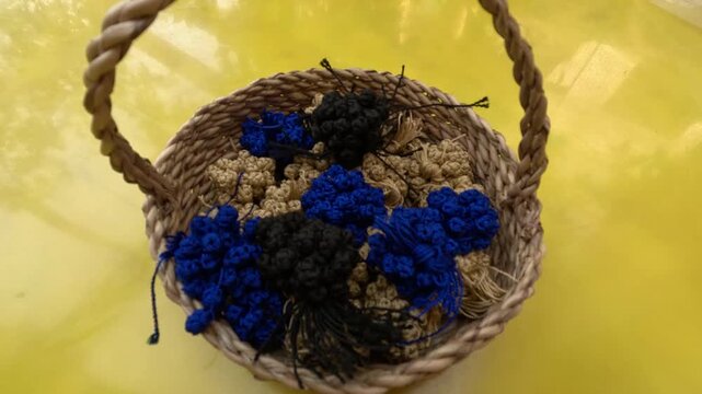 Small woven basket filled with Moroccan aqad knots, handmade textile fasteners used in traditional caftans and djellabas, showcasing artisanal craftsmanship, precision and cultural heritage.