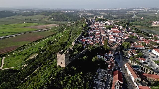 Castelo de Obidos and the medieval village within the stone walls. Scenic landscape and ancient fortification in Central Portugal, cinematic aerial panning view