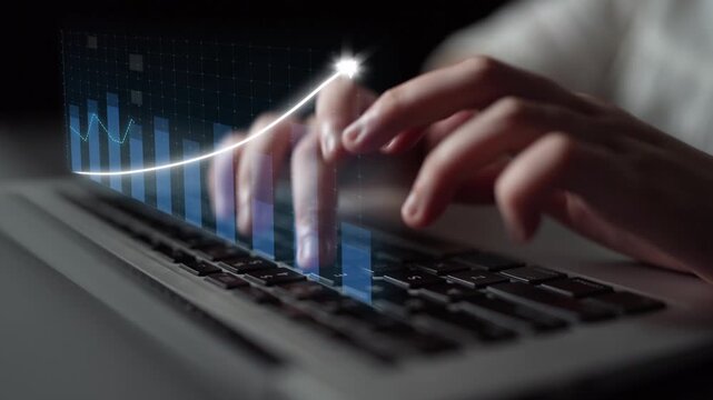 A close-up view of hands typing on a laptop with a virtual graph overlay, symbolizing financial growth and data analysis in a professional workspace. Copula
