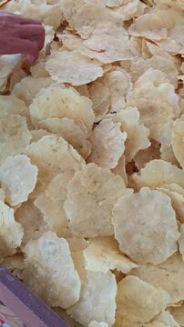 Crunchy Indonesian Emping Crackers for Sale and Selecting by a Local Customer