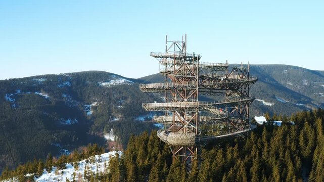 Aerial view of the Sky Walk tower shrouded in winter clouds above a snow-covered mountain valley in Dolni Morava, Czech Republic.