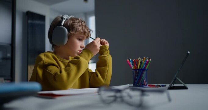 Young Student Concentrating Deeply While Jotting Notes During Remote Learning Session At Residence