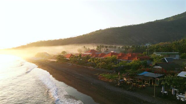 Aerial view of a tropical luxury resort with pool near a black sand beach