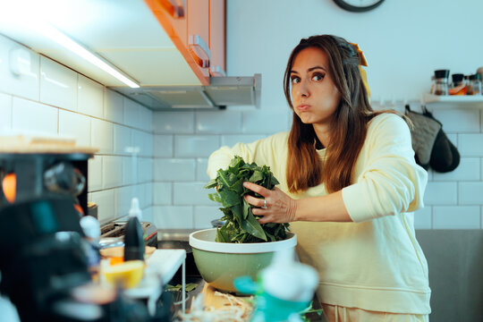 Puzzled Woman Holding Fresh Patience Dock Leaves Ready to Cook. Confused home cook clutching wet spinach dock greens preparing a meal at home