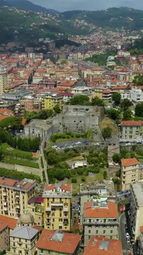 Vertical video. La Spezia, Italy. Castello San Giorgio, a medieval Genoese fortress of stone bastions and crenellated ramparts, Drone footage above terracotta rooftops and the Ligurian coast.. Drone 