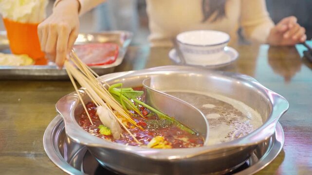 Female tourist eating original mala spicy hot pot (Chuan Chuan) at restaurant in Chengdu, China