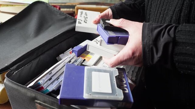 Close-up of hands searching through old CDs and cassette tapes, evoking nostalgia and personal archives. Ideal for themes of memory, retro culture, and rediscovery of analog media.