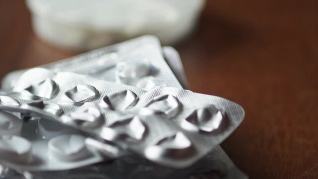 Close-up of used foil pill packs accumulating on a table, symbolizing ongoing treatment, consumption, and long-term health management.