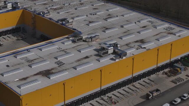 Logistics warehouse near Autostrada A1 in Po Valley Emilia Romagna Italy with storage yard, truck loading area and industrial distribution infrastructure, drone lateral pan to left