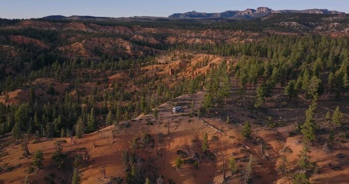 Rolling sandstone hills dotted with pine trees in Dixie National Forest Utah high desert landscape, drone orbit