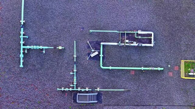 Overhead drone shot of industrial pipes, fittings, and valve clusters on rooftop - Latvia architecture