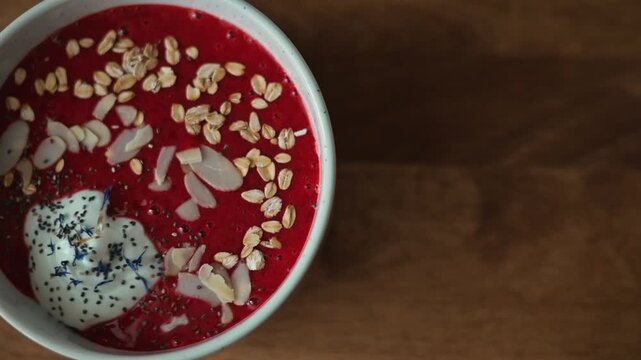 A top-down view shows a bowl of raspberry yogurt topped with almonds, poppy seeds, and granola.