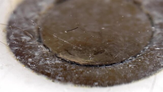 Unhygienic clogged metallic drain with hair and soap scum macro