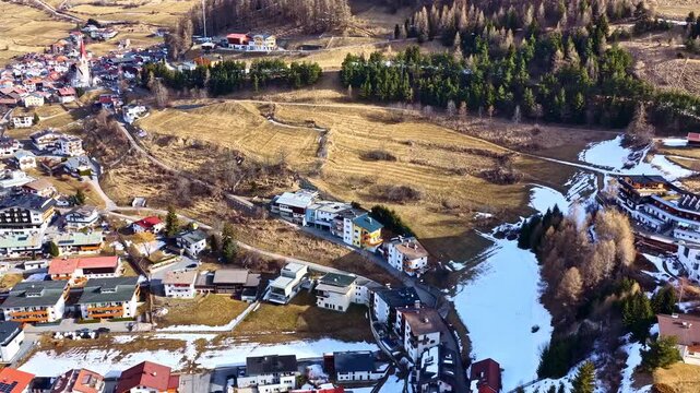 Drone panorama of a European mountain town with snow patches, forest and church spire - Nauders, Austria