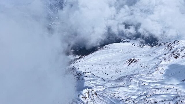 Dramatic drone shot of snowy mountain ridges rising above a thick cloud layer - Nauders, Austria