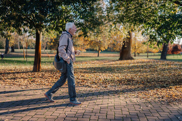 Fototapeta premium Senior man walking with coffee in autumn park