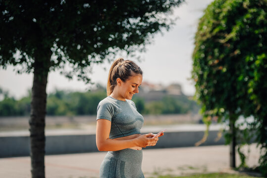 Sportswoman using smartphone app after training outdoors in city park
