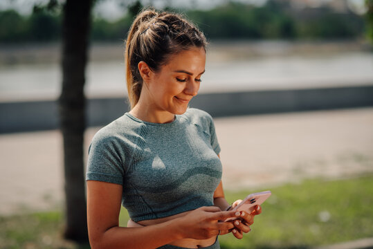 Sportswoman using smartphone app after training outdoors