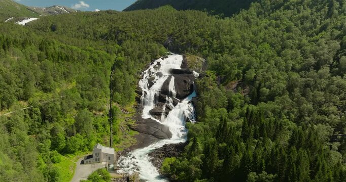 Drone captures the powerful Tveitafossen waterfall in Norway&rsquo;s Husedalen Valley, highlighting a hydropower station surrounded by dramatic mountains and flowing river scenery.