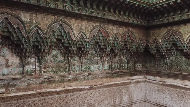 Wide view of a Moroccan interior corner featuring ornate carved arches, detailed plasterwork, and zellige tiles. Rich textures and symmetry ideal for architecture and design visuals.
