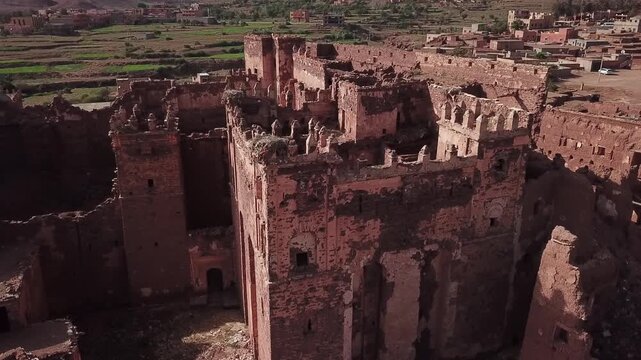 Drone close view of ancient kasbah ruins tower in Ouarzazate showing weathered adobe walls and historic decay. Strong texture and heritage feel ideal for cinematic and documentary visuals.