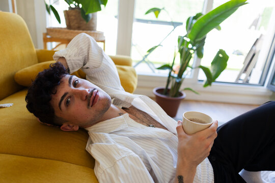 Young man relaxing on couch drinking coffee